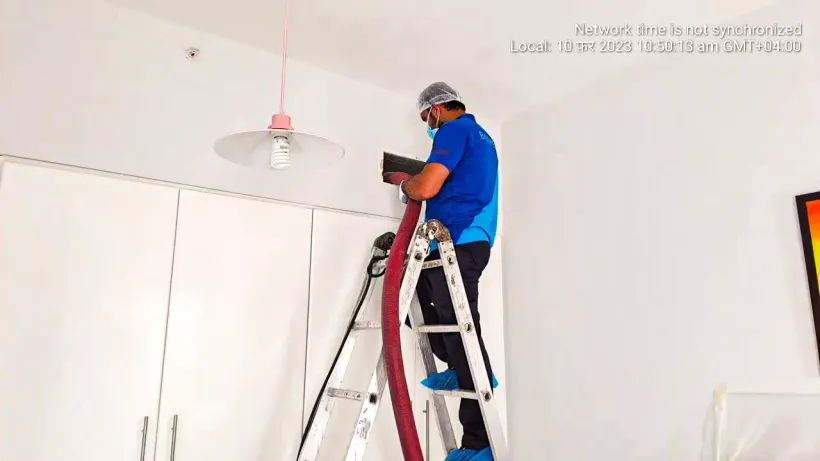 Technician on a ladder accessing a ceiling supply grille